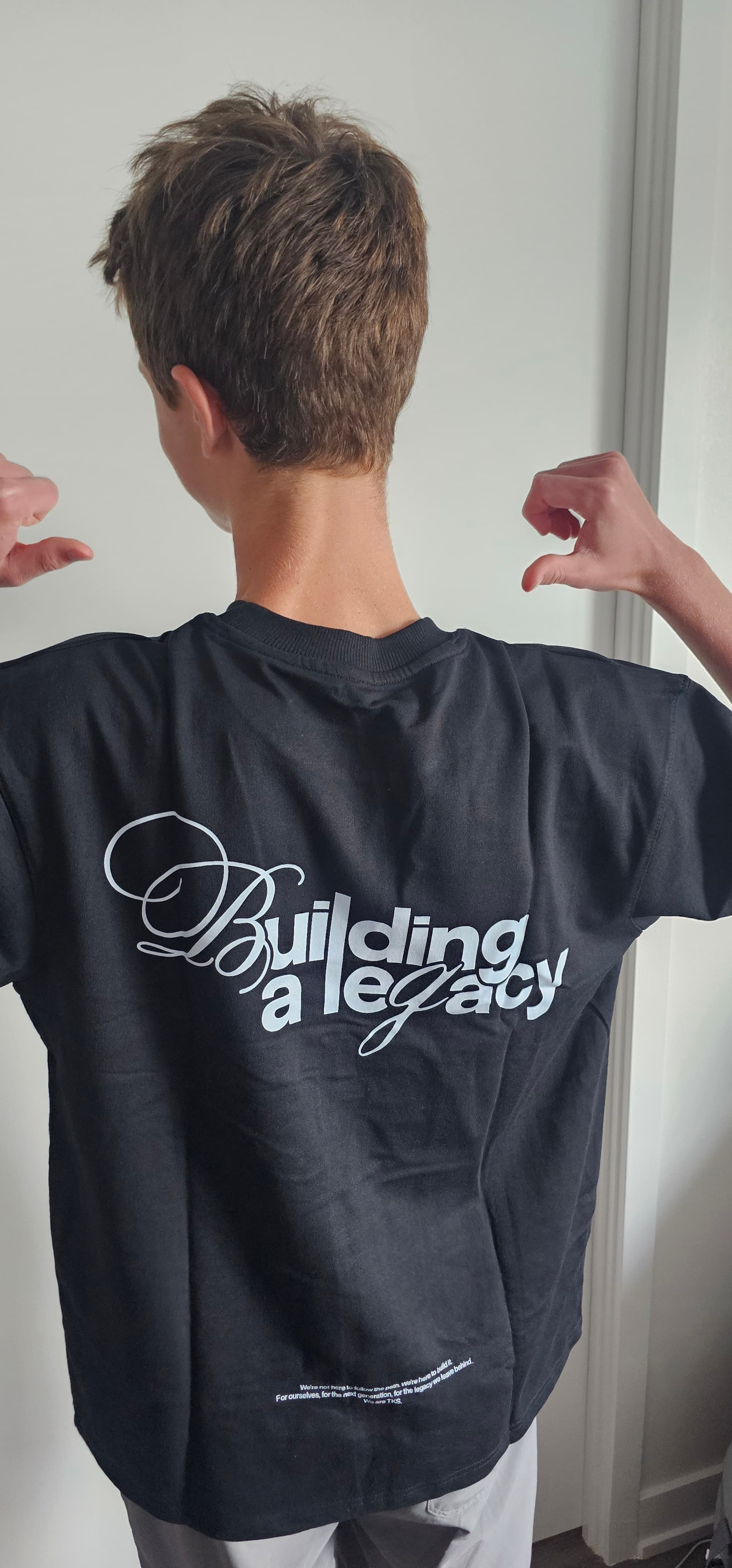 Rear view of a person wearing a black t-shirt with white "Building a legacy" text.